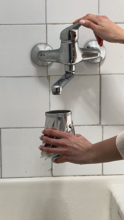 Filling the Turbo Moka boiler with water under a wall-mounted tap in a white-tiled kitchen